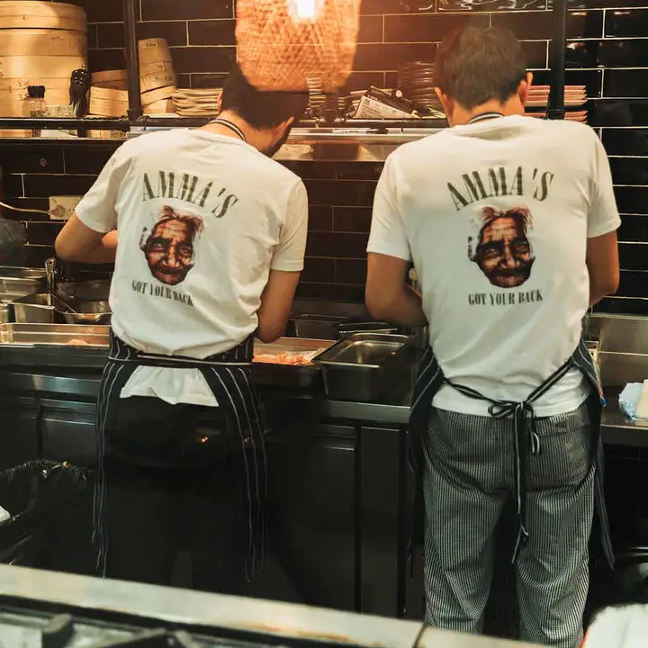 Chefs in the open kitchen wearing Amma's Got Your Back shirts